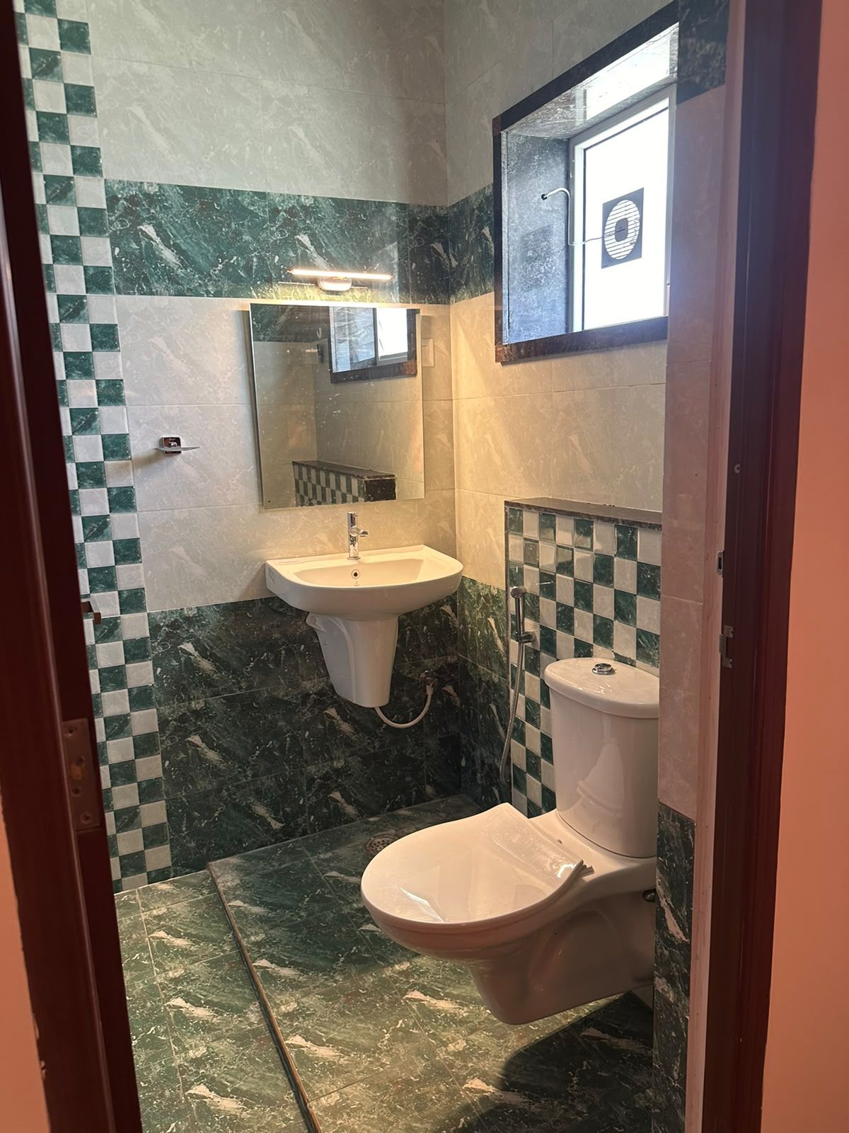 Un baño con lavamanos, inodoro y espejo.