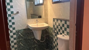 Un baño con lavamanos, inodoro y espejo.