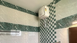 A bathroom with a checkered tile wall, a marble floor, a white toilet, and a shower area with a handheld showerhead. - MV Home Stay (Thirumangalam)