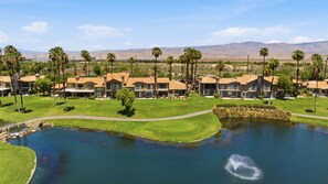 A golf course with a pond, palm trees, and houses with a mountain backdrop. - Palm Valley Oasis with Golf Course & Lake Views (Palm Desert)