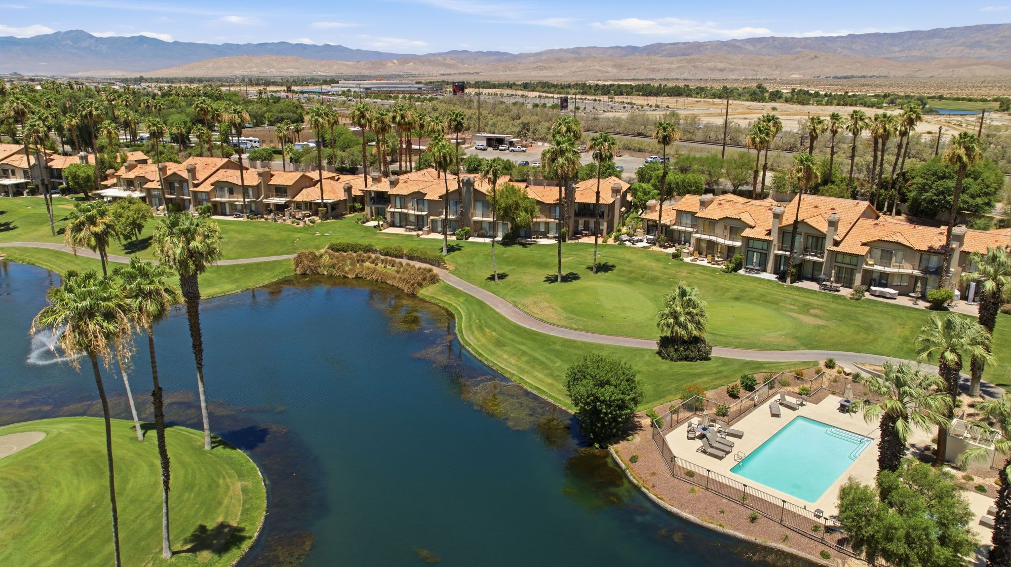 A golf course with a swimming pool, surrounded by residential buildings with red-tiled roofs.