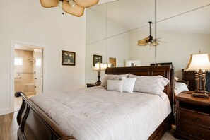 Ein Schlafzimmer mit einem großen Bett, Nachttischen, einem Deckenventilator und einem Spiegel.