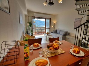 A dining area with a table set for two, a bottle of water, and a bowl of bread. - Apartment in Acquaseria With Terrace (San Siro)