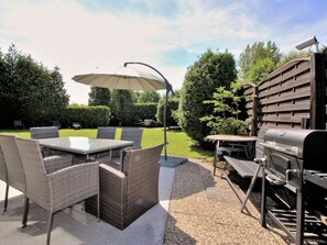 An outdoor patio with a table and chairs, a grill, and a large umbrella. - Holiday Home With 4 Bedrooms (Scharbeutz)