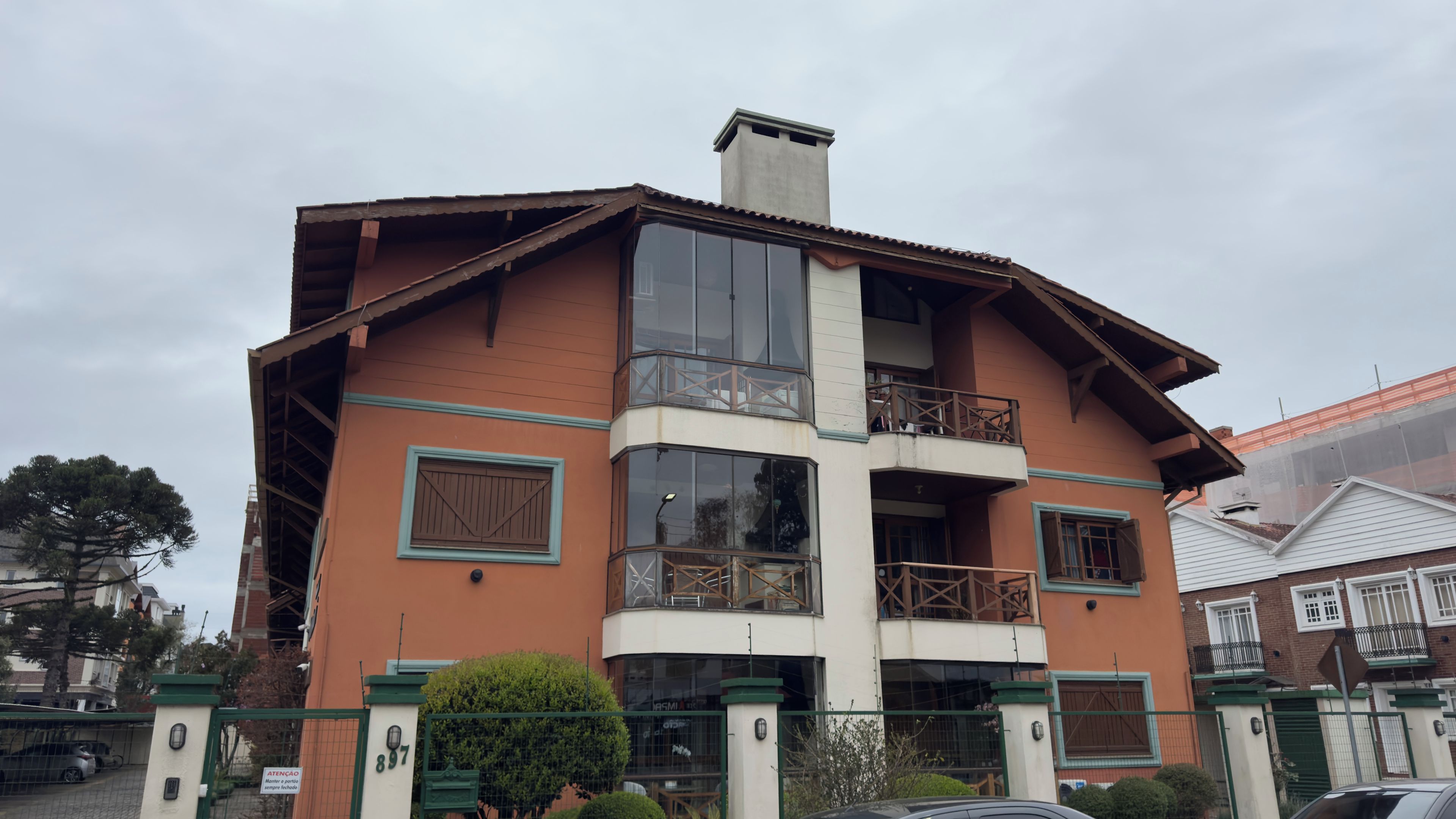 A two-story building with a balcony on the second floor, a gated entrance, and a chimney.