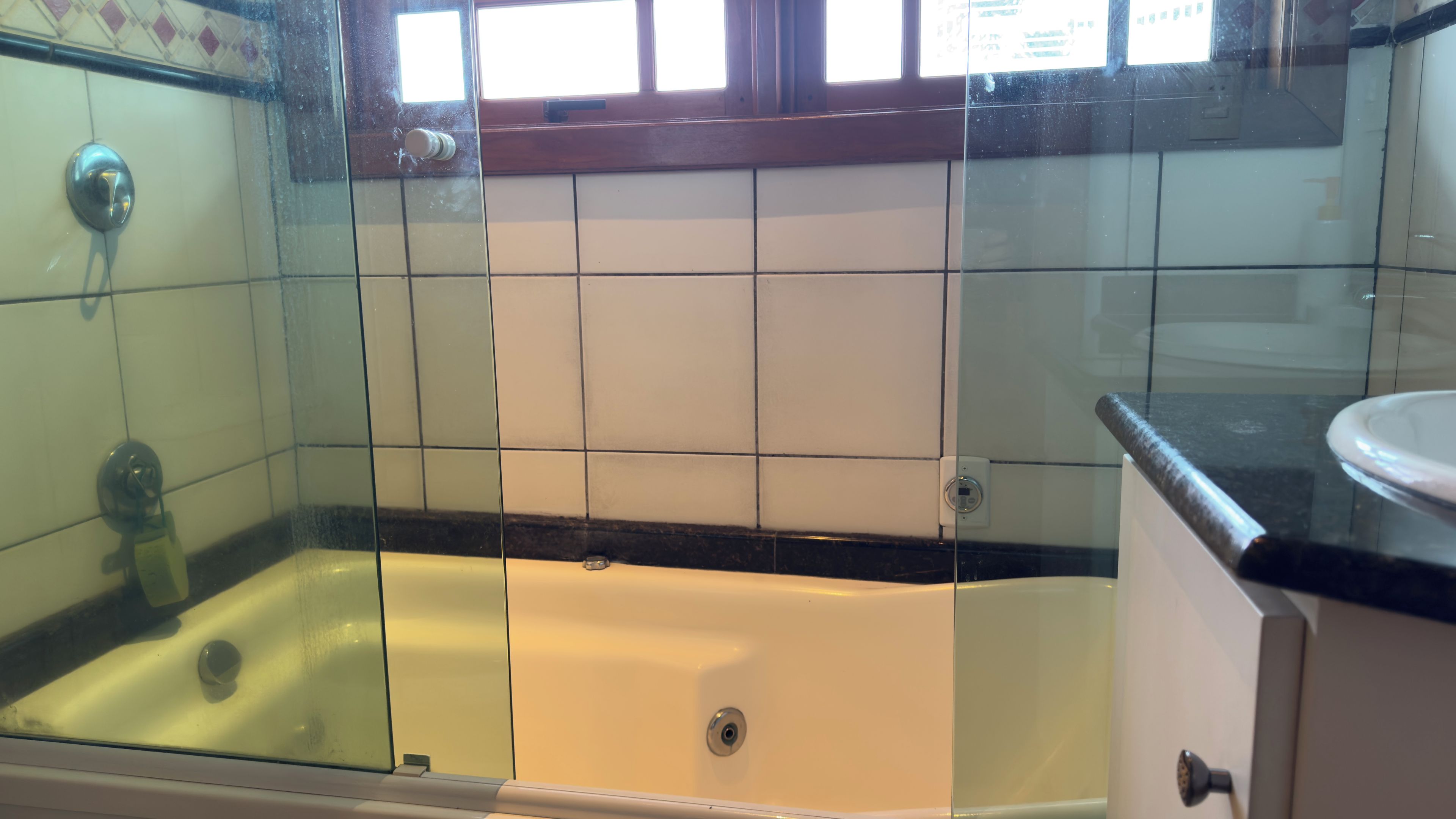 Um banheiro com banheira, box de vidro e pia com bancada.