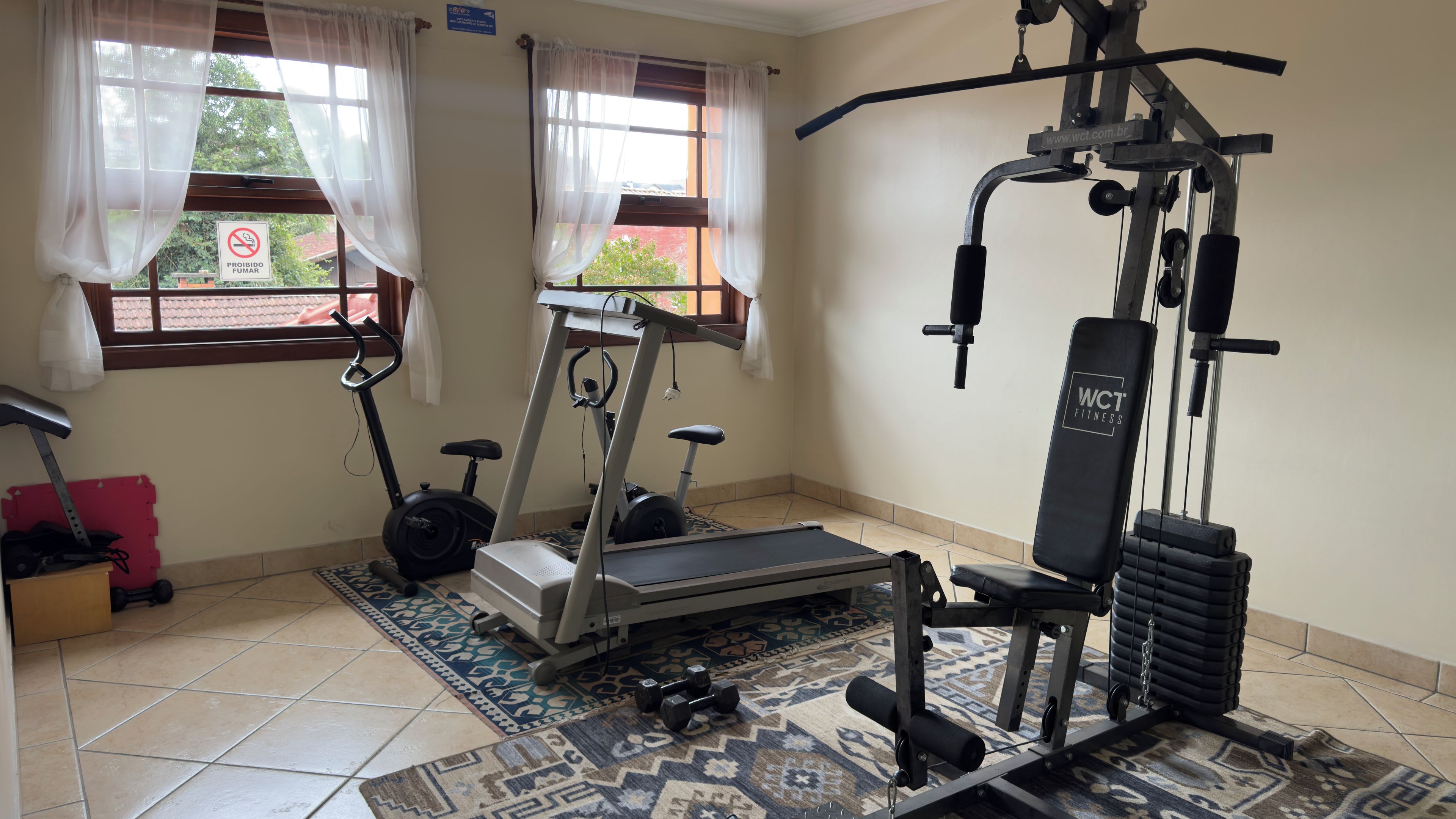 A home gym with a treadmill, elliptical, and weight bench.