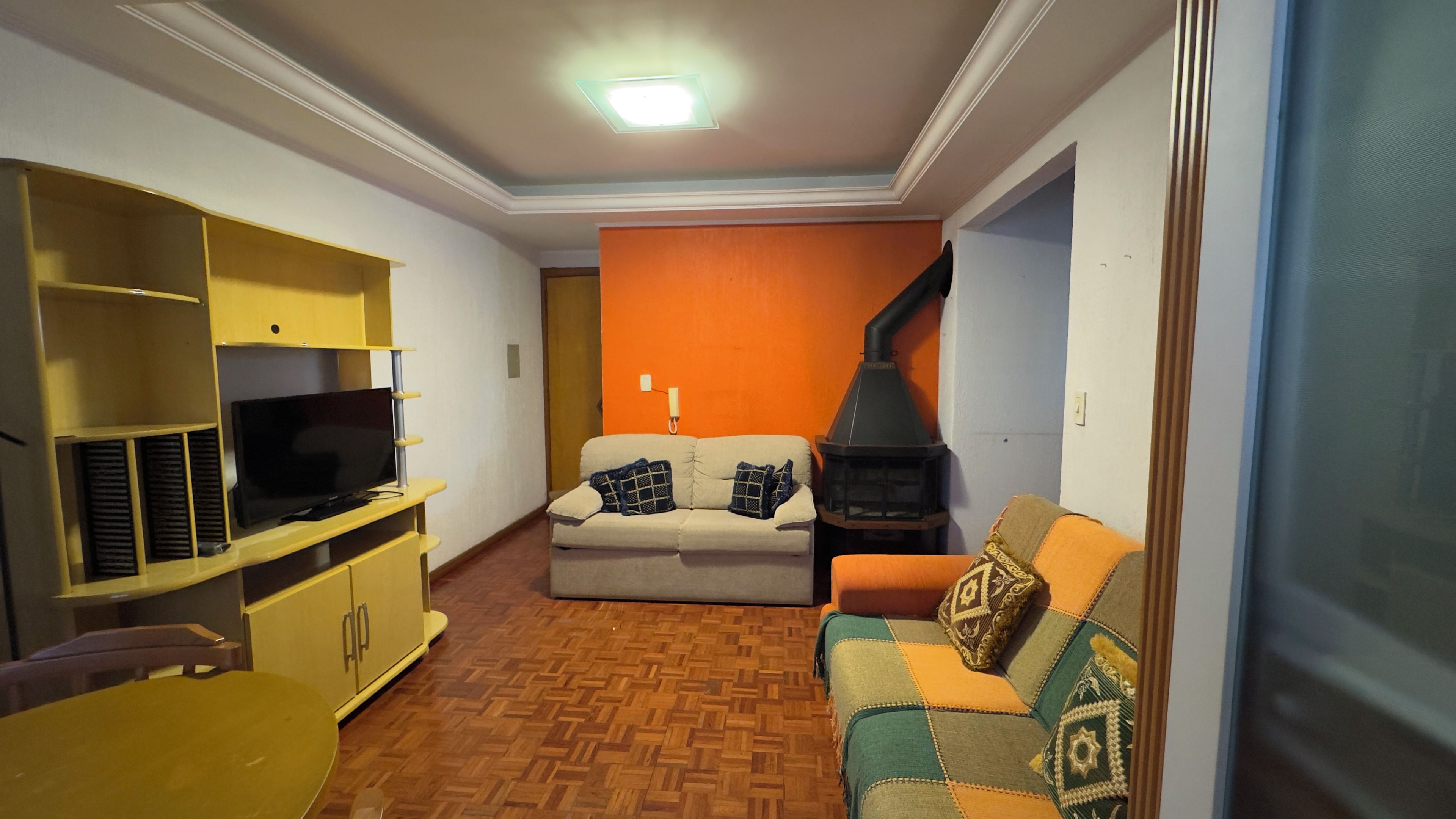 A living room with a television, sofa, and a fireplace.