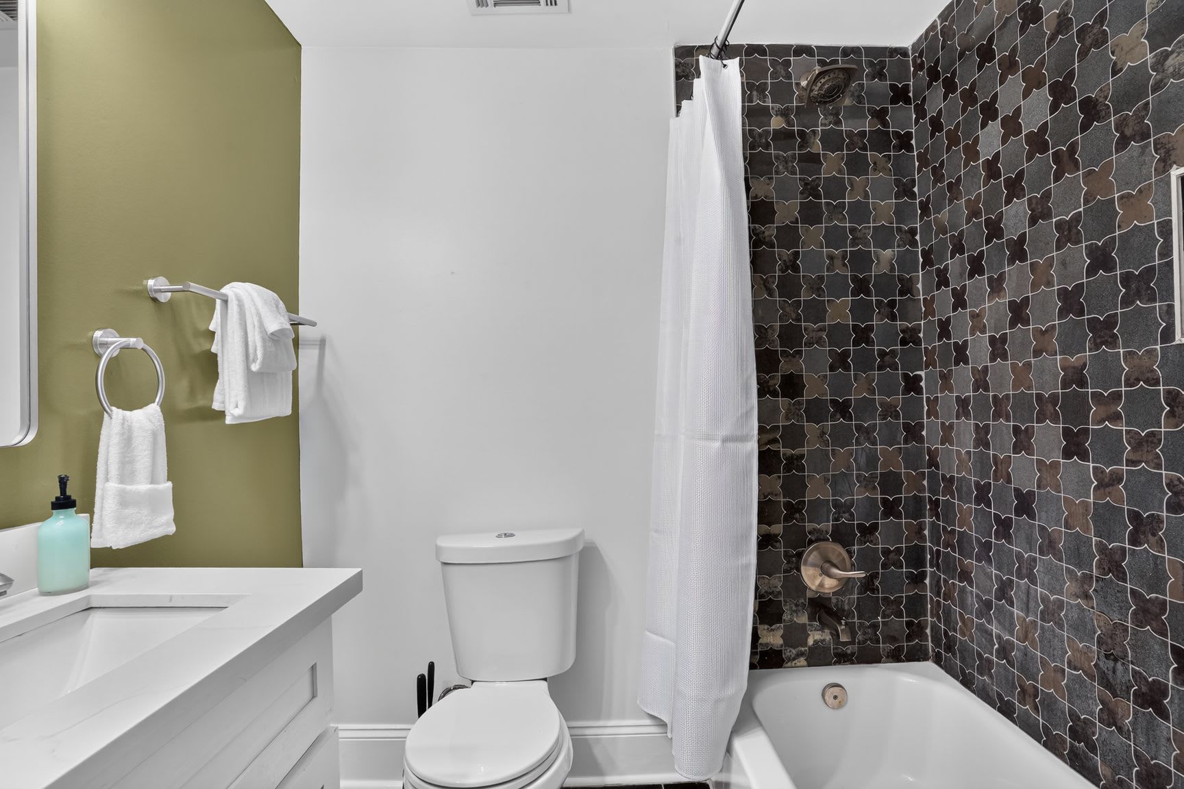 Une salle de bain avec des toilettes blanches, une baignoire et un rideau de douche.