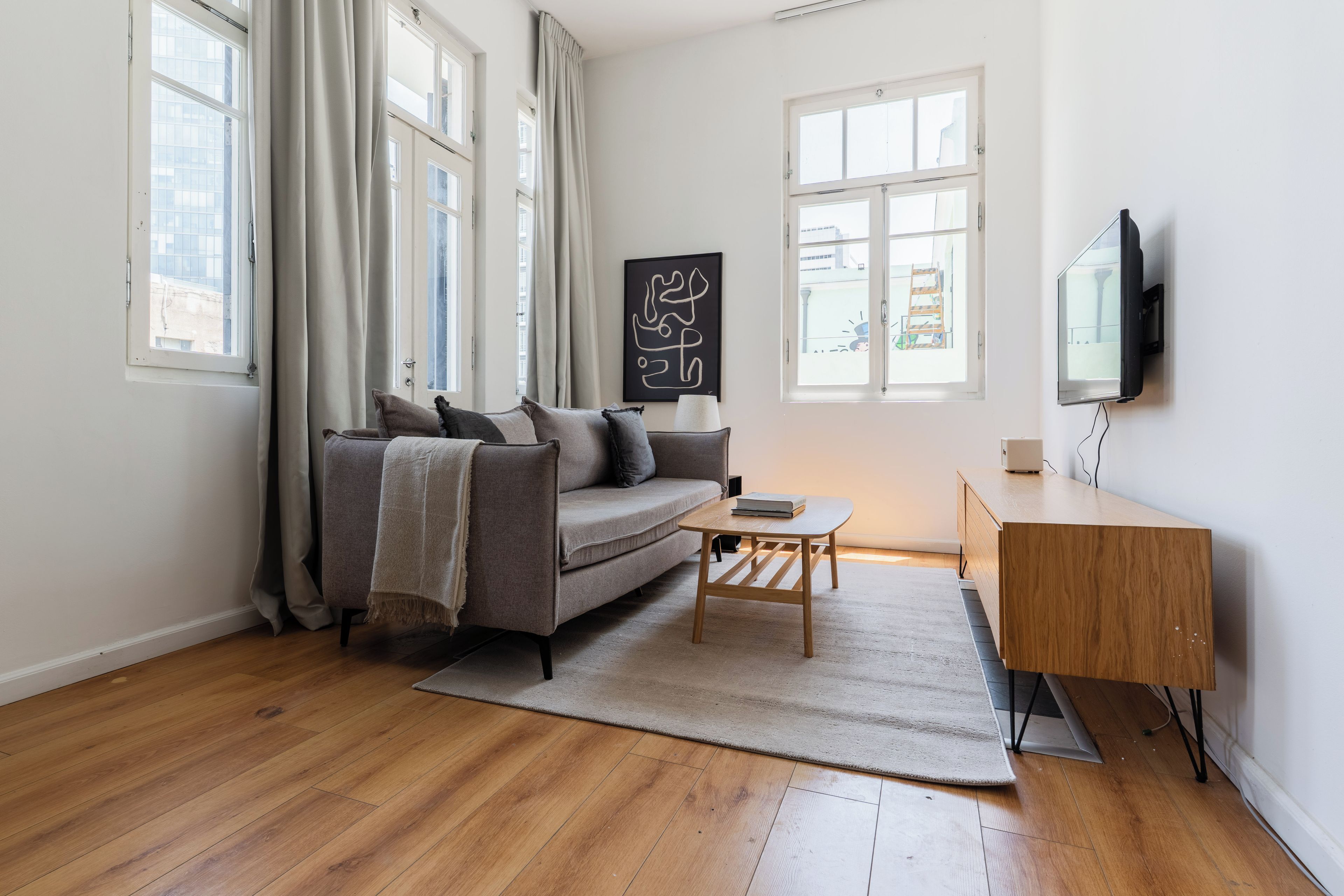 Ein modernes Wohnzimmer mit einer Couch, einem Couchtisch und einem Fernseher auf einer Holzkommode.