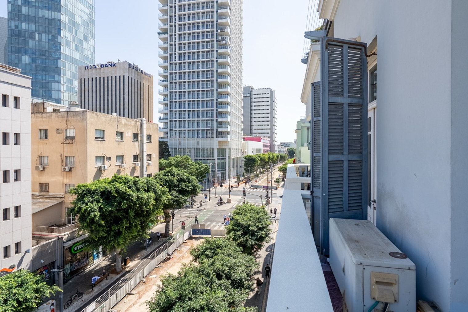 A cityscape with modern buildings, a clear sky, and a pedestrian street.