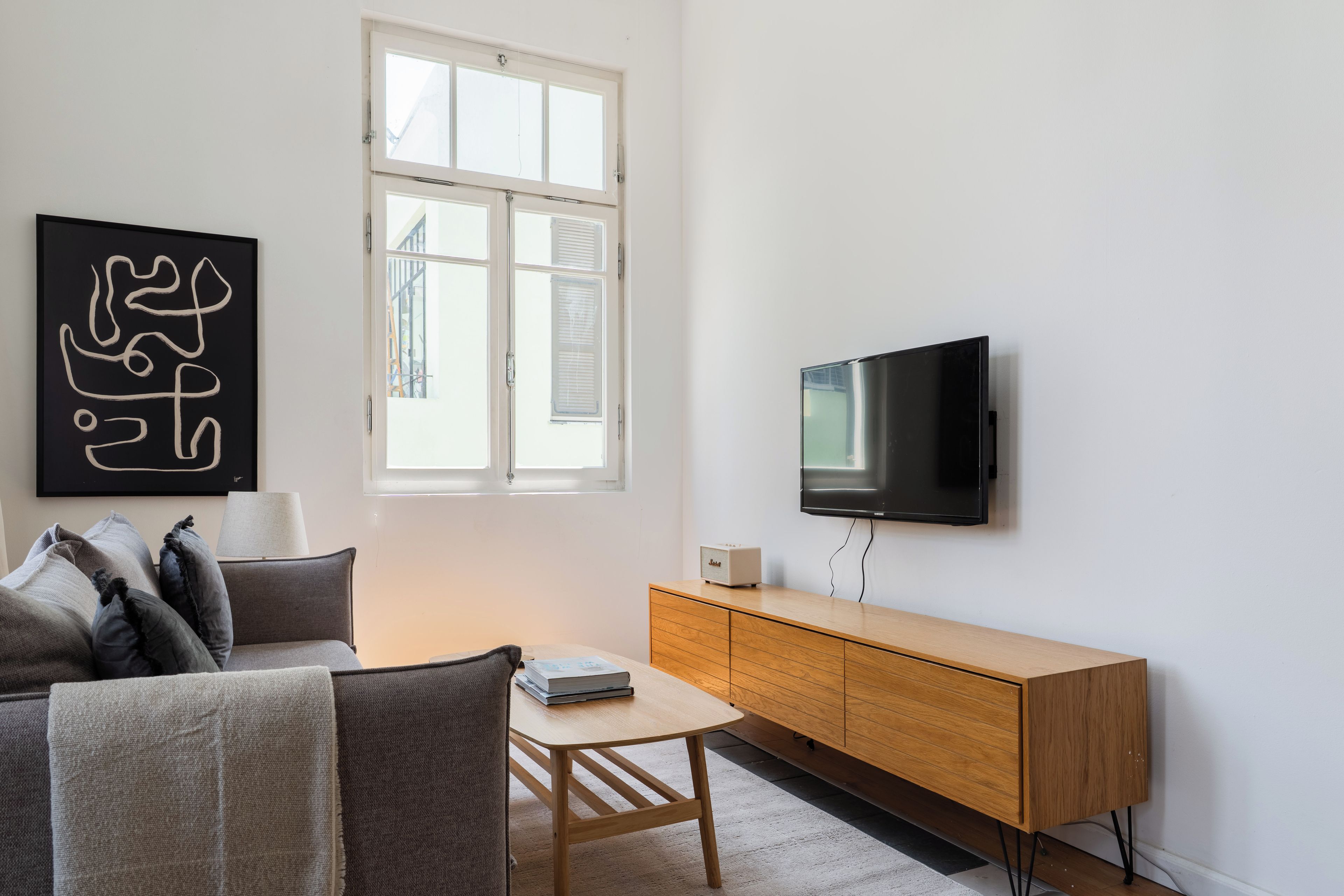 A modern living room with a sofa, a coffee table, a television, and a cabinet.