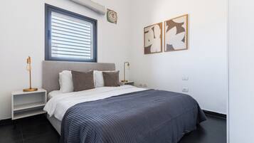 Een moderne slaapkamer met een bed, nachtkastjes, een raam met zonwering, een wandklok en abstracte kunst.