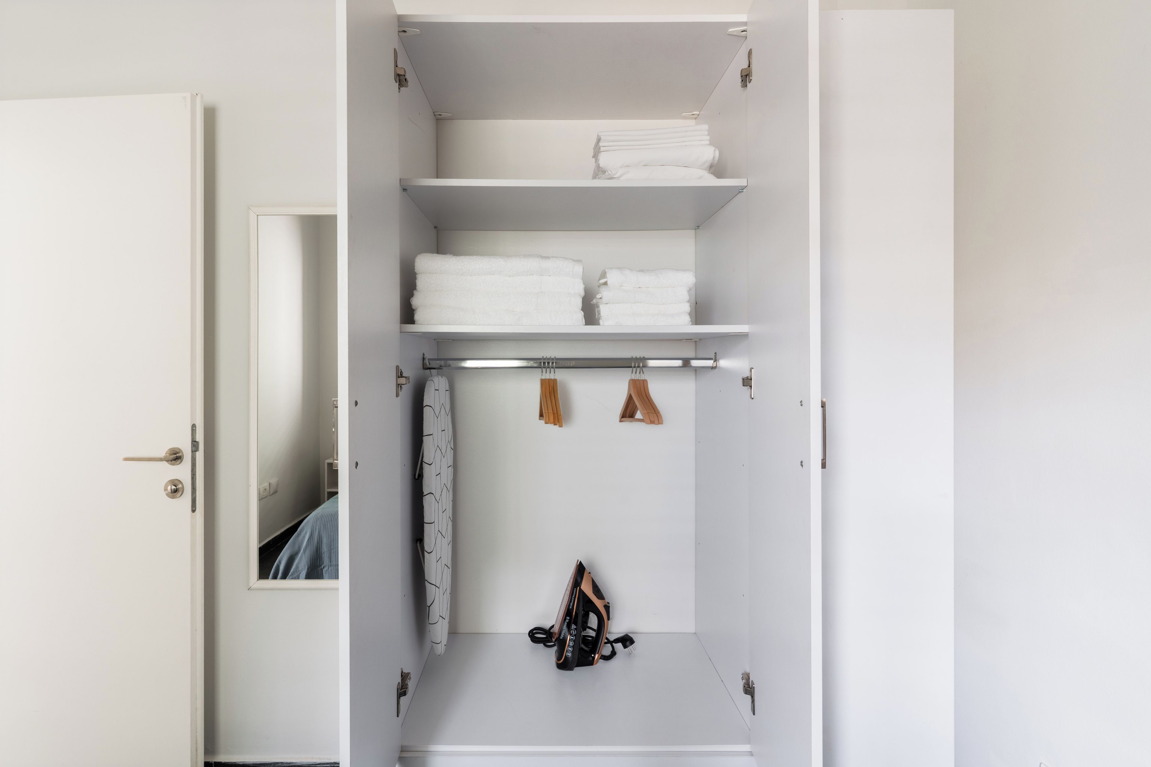 A white wardrobe with multiple shelves, a hanging rack, and a door with a keyhole.