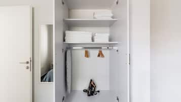 A white wardrobe with multiple shelves, a hanging rack, and a door with a keyhole.