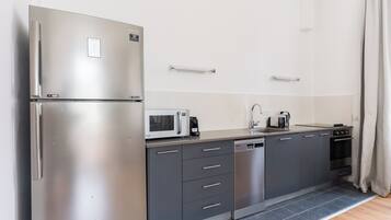 A modern kitchen with a stainless steel refrigerator, microwave, dishwasher, and a built-in oven.
