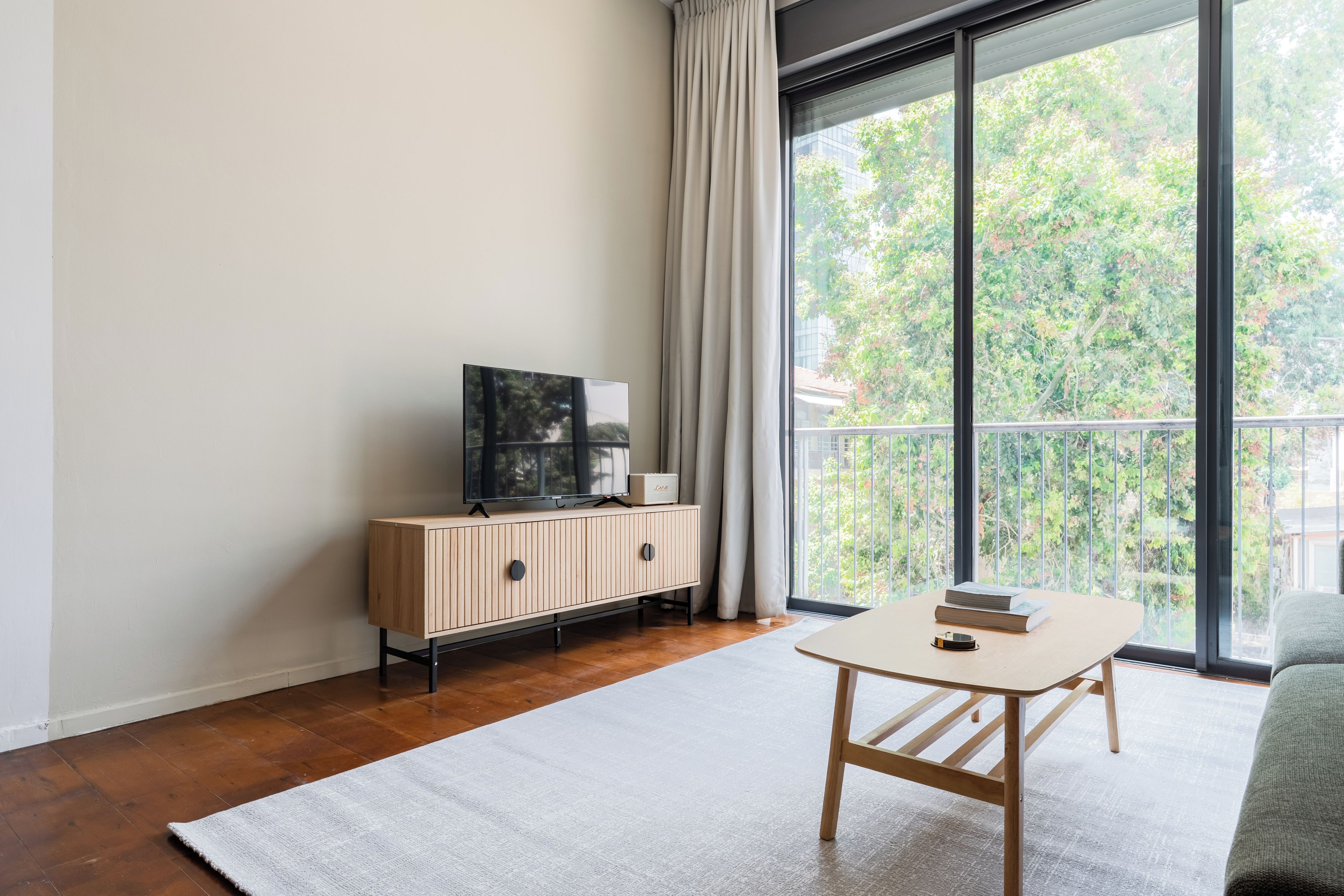 Ein modernes Wohnzimmer mit einem Holzkabinett, einem Flachbildfernseher und einem Tisch mit Büchern.
