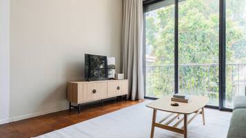 Ein modernes Wohnzimmer mit einem Holzkabinett, einem Flachbildfernseher und einem Tisch mit Büchern.