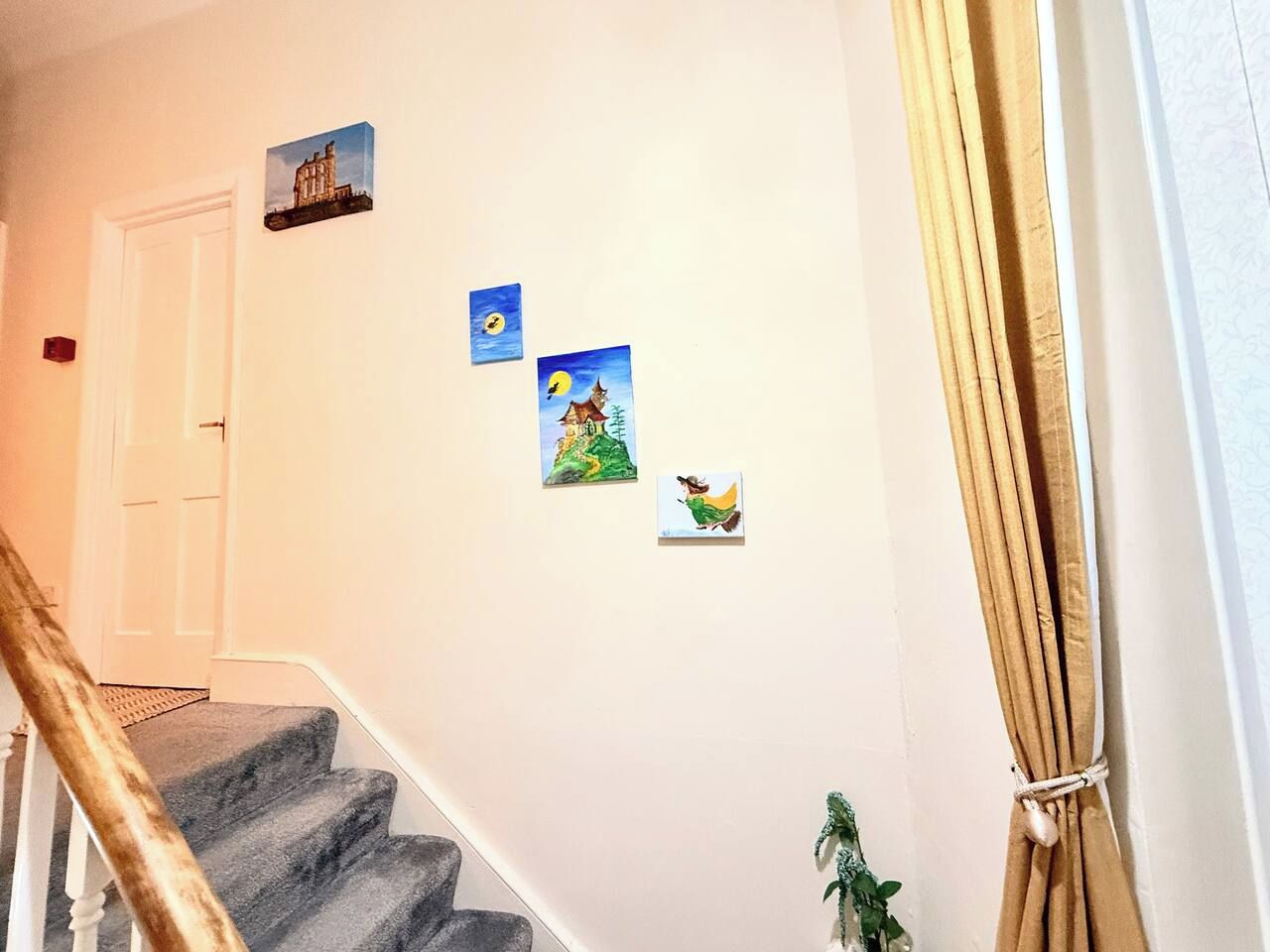 A staircase with a handrail, a door, and wall-mounted artwork.