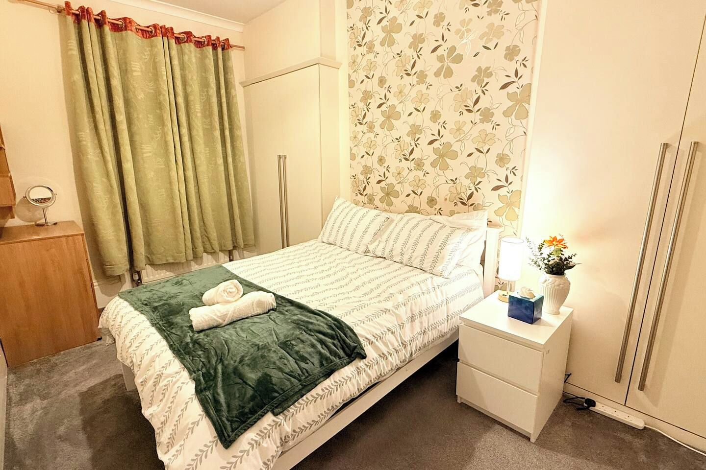 Une chambre d’hôtel avec un lit, une table de chevet, une lampe et un miroir.