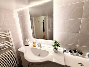A bathroom with a white sink, a mirror, a towel rack, and a potted plant. - Spacious 3 Double BR | 5 mins to city | Sleeps 6 (Tyne and Wear)