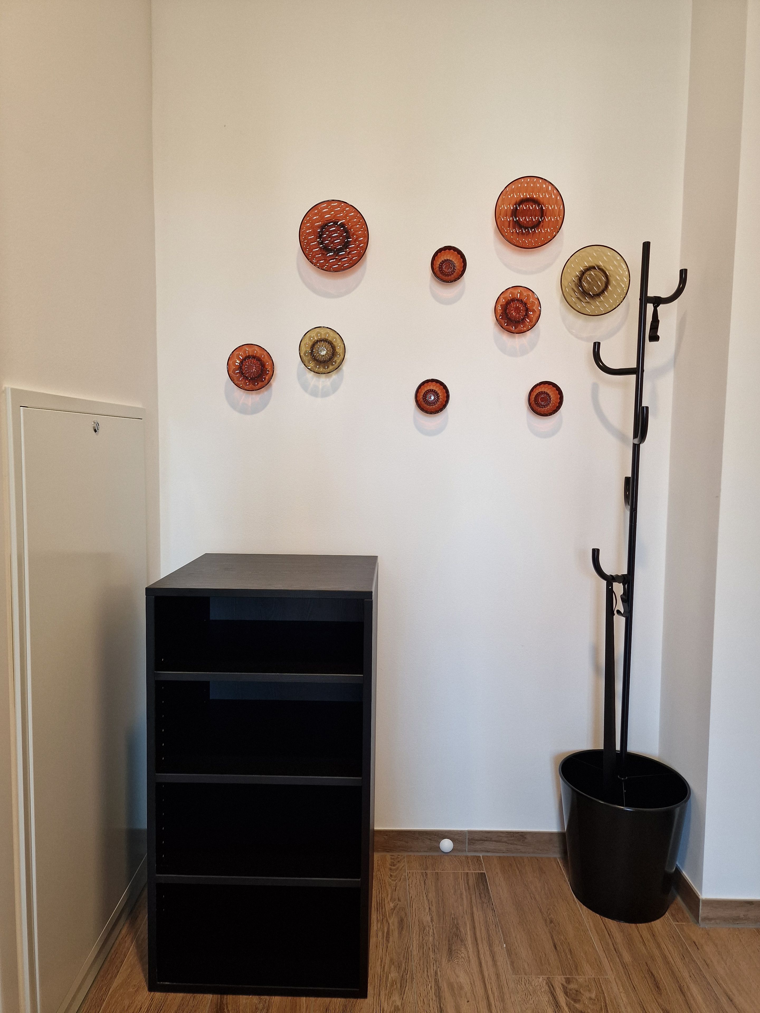 Una habitación con un mueble negro para guardado, un perchero negro y placas decorativas en la pared.