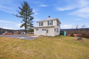 A two-story house with a front porch, a garage, and a large tree in the yard. - Historic Wardensville Home w Mountain Views (Wardensville)