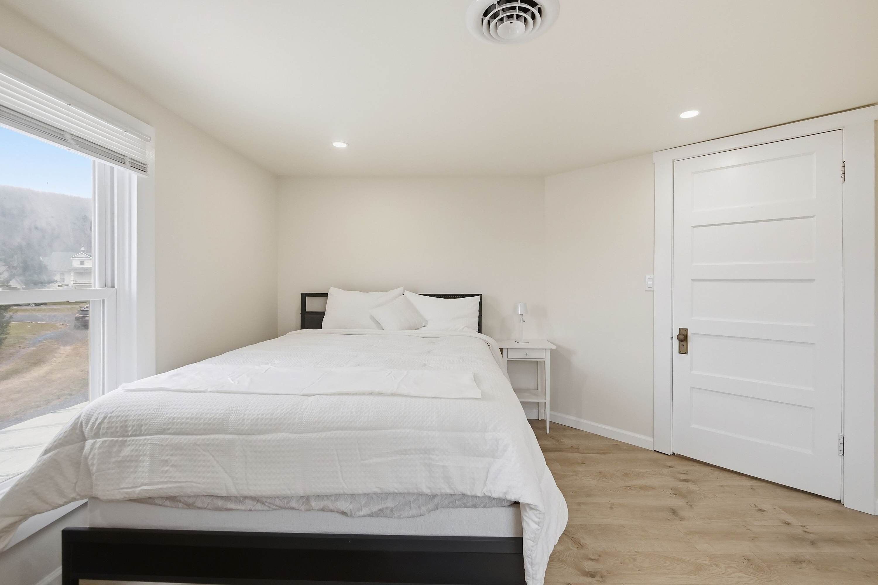 Une chambre à coucher avec un lit, une table de chevet, une lampe et une porte.