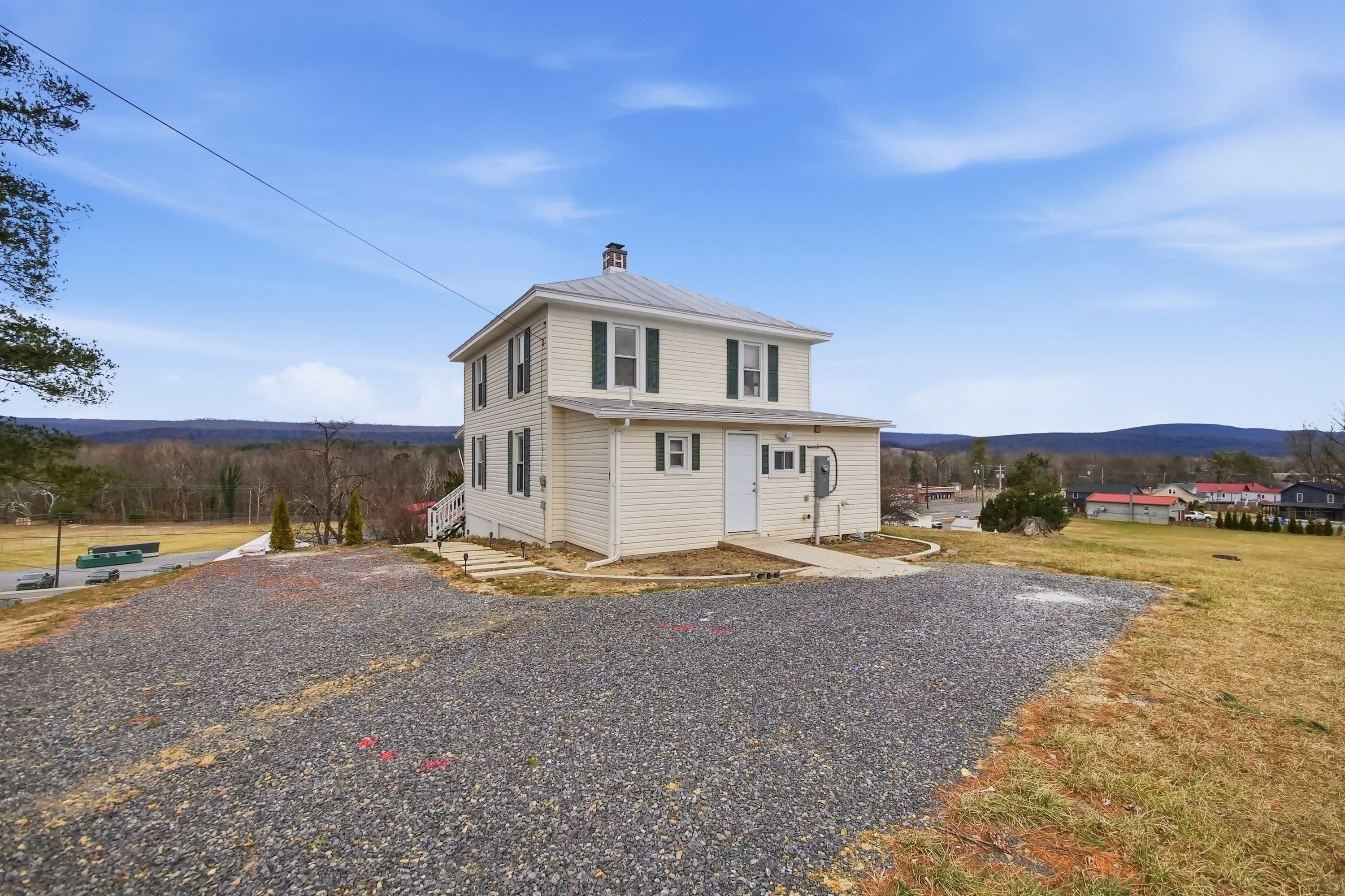 A two-story house with a gravel driveway and a small front yard.