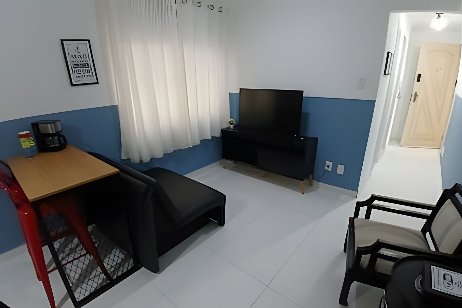 A compact living space with a TV, a small table, a sofa, and a chair.