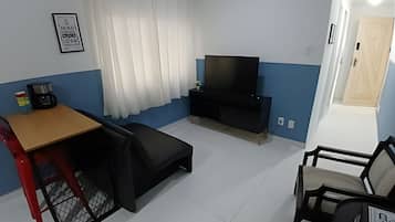 A compact living space with a TV, a small table, a sofa, and a chair.