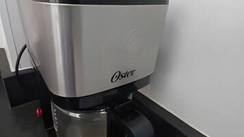 Een koffiezetapparaat met een transparante waterreservoir en een zwart opvangbakje.