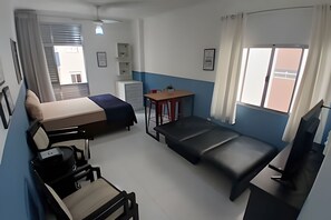 A room with a bed, a desk, a chair, a TV, and a window. - SHB - Aconchego a Passos do Mar (Santos)