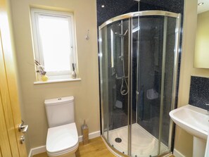 Ein Badezimmer mit Toilette, Duschkabine, Fenster und Waschbecken.