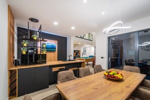 Eine moderne Küche mit einer Holztischinsel, einem Essbereich mit Holztisch und einem Billardtisch im Hintergrund.