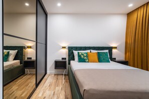 Ein modernes Schlafzimmer mit einem großen Bett, zwei Nachttischen, einem Spiegel und einer Schiebetür.