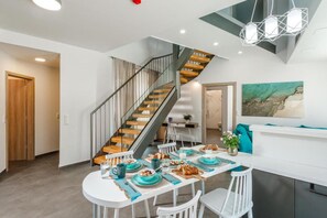A modern kitchen with a dining area, a staircase, and a view of the sea. - Coastal Villa with a Pool for 6 in Syvota, Greece (Syvota)
