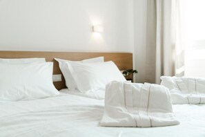 A hotel room with a neatly made bed, a wooden headboard, and a wall-mounted light fixture. - Coastal Villa with a Pool for 6 in Syvota, Greece (Syvota)