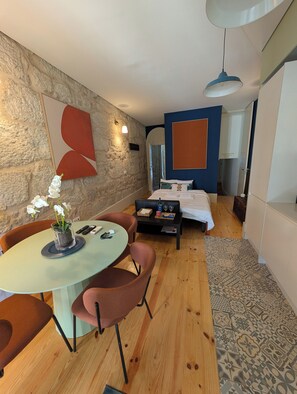 A compact room with a bed, a dining area with a table and chairs, a stone wall, and a blue accent wall. - Charming Porto House with Private Garden on Time Out's Coolest Street (Porto)