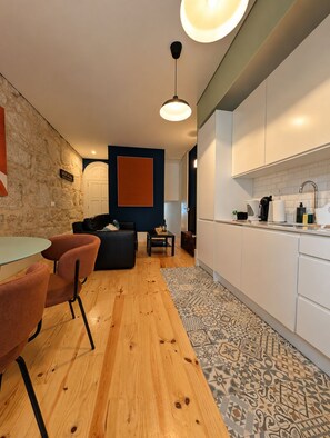 Een moderne keuken met witte kasten, een houten eettafel en een vloerkleed met een patroon.