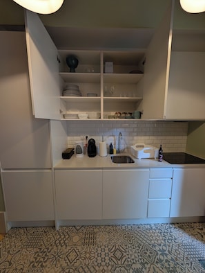 Eine Küche mit weißen Schränken, einer gefliesten Spritzschutzwand und einem gemusterten Boden.