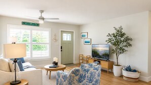 A living room with a sofa, armchair, TV, and a plant. - The McKenzie House (Punta Gorda)