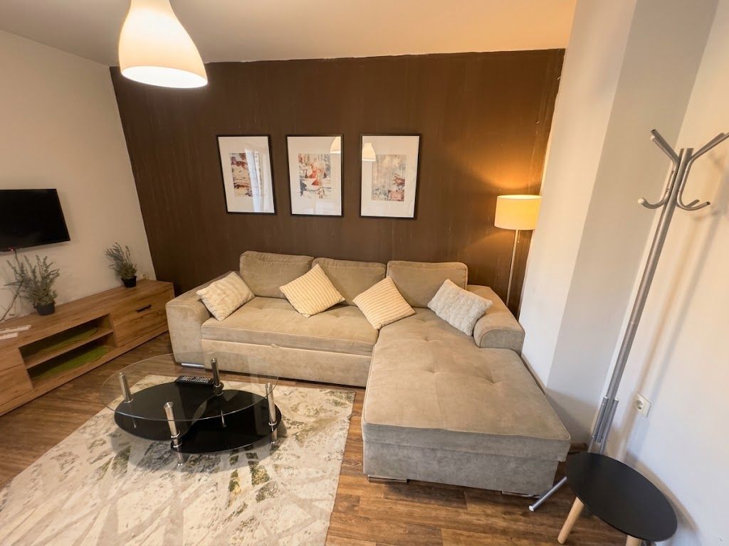 A living room with a sectional sofa, a coffee table, a TV, and framed artwork on the wall.