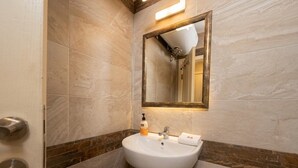 Une salle de bain avec un lavabo blanc, un miroir et un porte-serviettes.