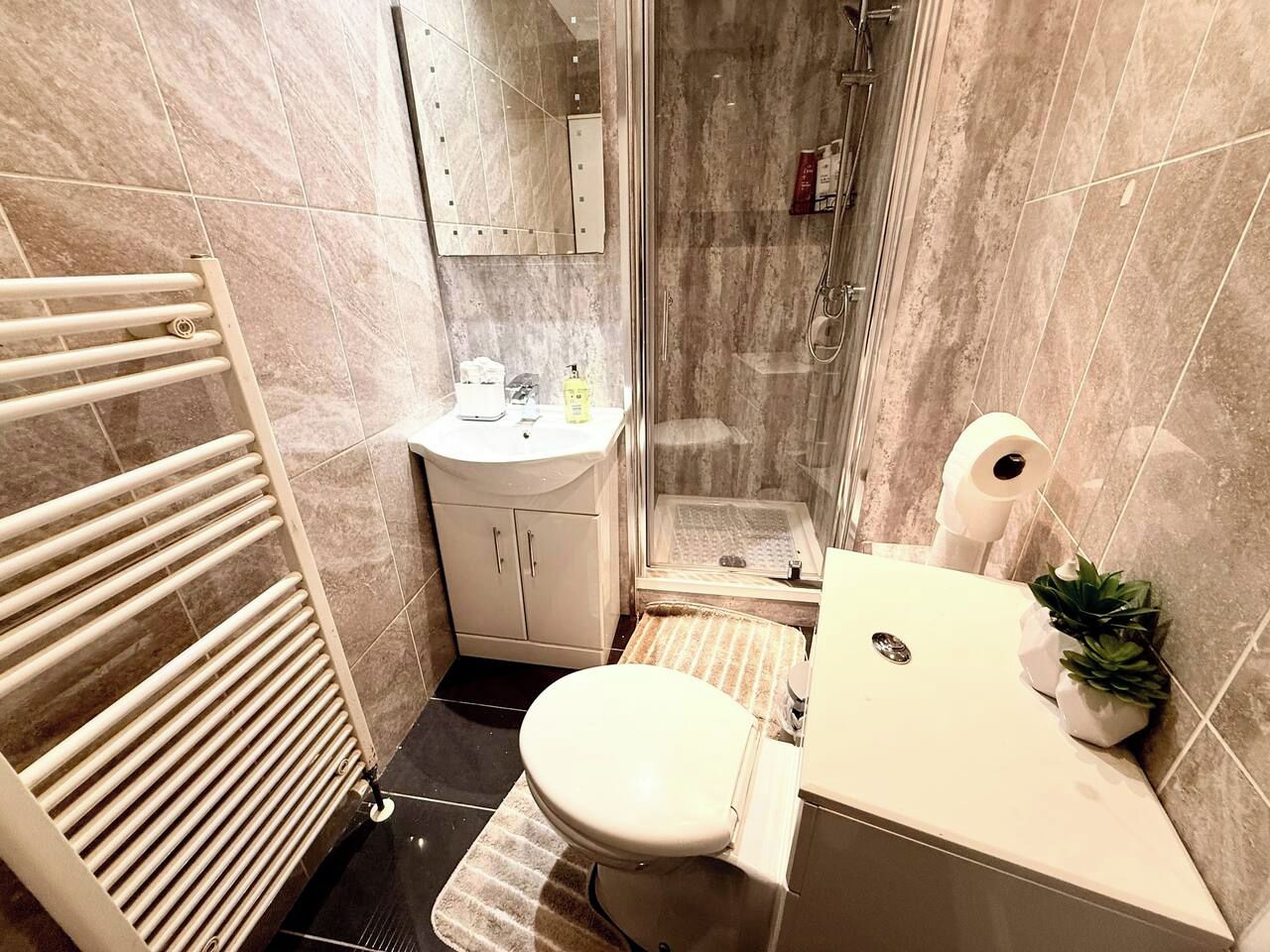 A bathroom with a toilet, sink, shower, and a towel rack.
