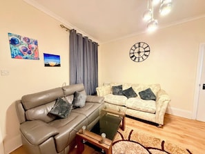 A living room with a sofa, a coffee table, and a wall clock. - Spacious 1BR, Two Beds | 5 mins to city | Sleeps 3 (Tyne and Wear)