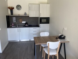 Una cocina moderna con una mesa y sillas de madera, un microondas y un reloj en la pared.