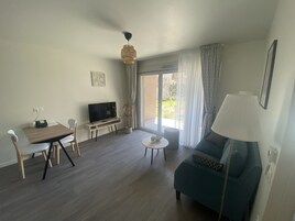 A living room with a TV, a dining table, a sofa, and a lamp.