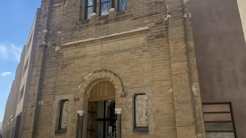 A historic building with a prominent arched entrance, a clock, and a sign indicating it is a museum.