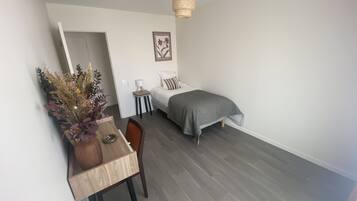 Un dormitorio pequeño y moderno con cama, mesita de noche, lámpara y un adorno en la pared.